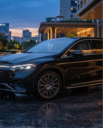 A dark SUV photographed at dusk outside a lit building